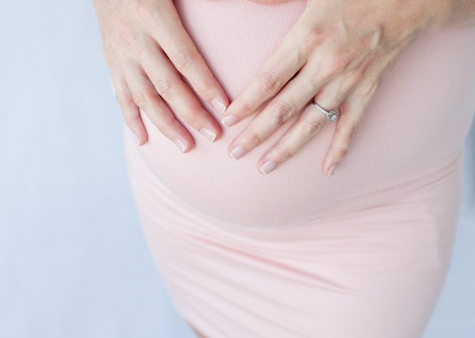 Pregnant mom makes heart with hands on pink maternity gown with jewels Gainesville Florida