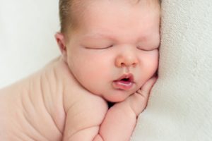 Newborn baby boy naked sleeping on white blanket close up of his face Gainesville newborn photographer