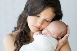 Gainesville newborn photographer beautiful new mom cradling her newborn girl close to her face both of them with eyes closed