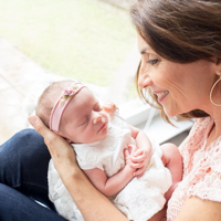 Gainesville newborn photographer holding newborn baby girl with pink headtie