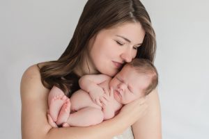 Mom totally in love cuddling her brand new naked newborn boy