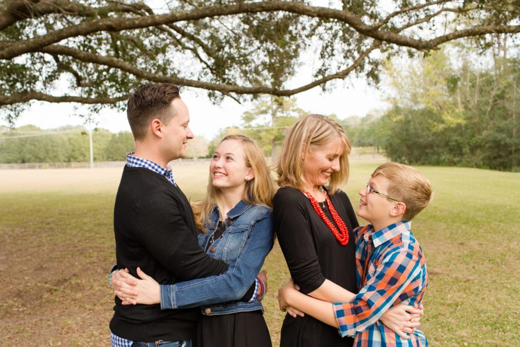 Family photos mom and dad hugging teenage son and daughter at their home i