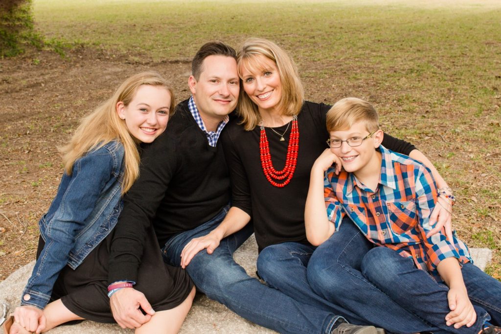 Family photos mom and dad with teen son and daughter at their home posed on grass