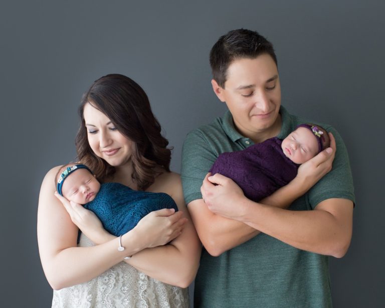 Newborn twin girls in mom dad arms teal and purple wraps and headties Gainesville Florida photos shoot