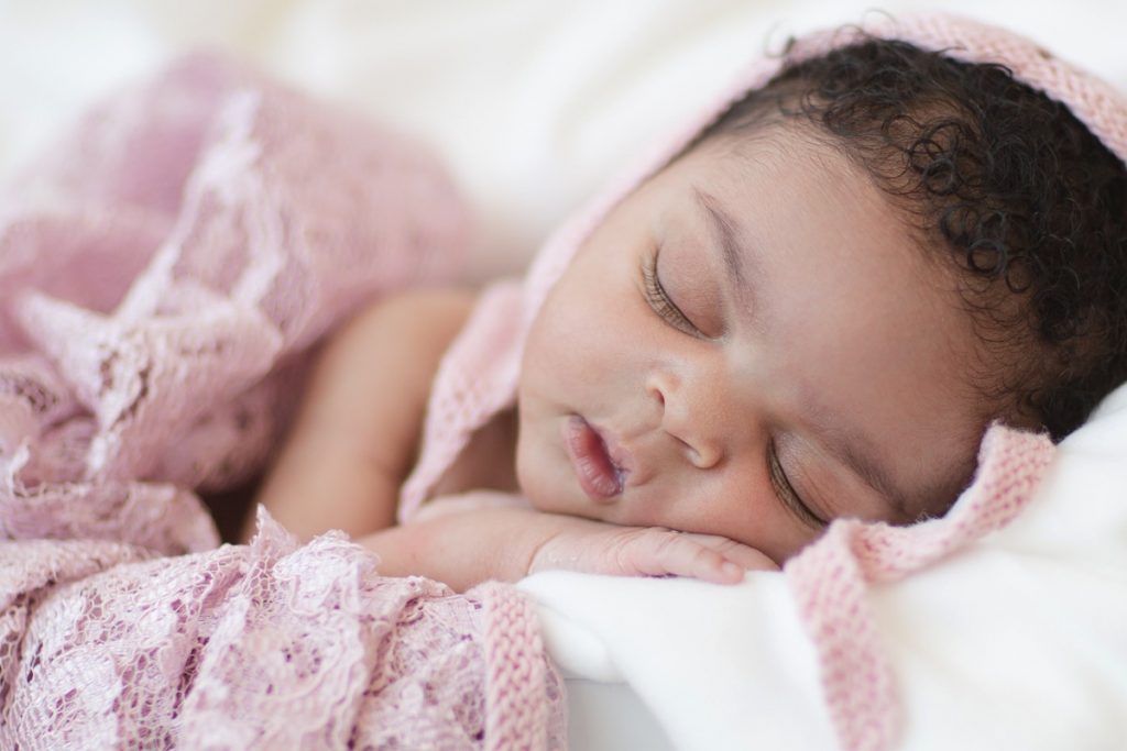 Newborn girl in buvket with pink lace and bonnet