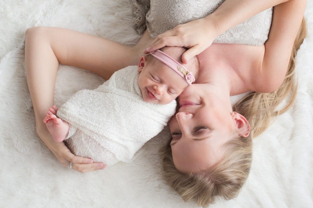 Mom and newborn girl on fur cuddling brand new baby photo Gainesville Florida