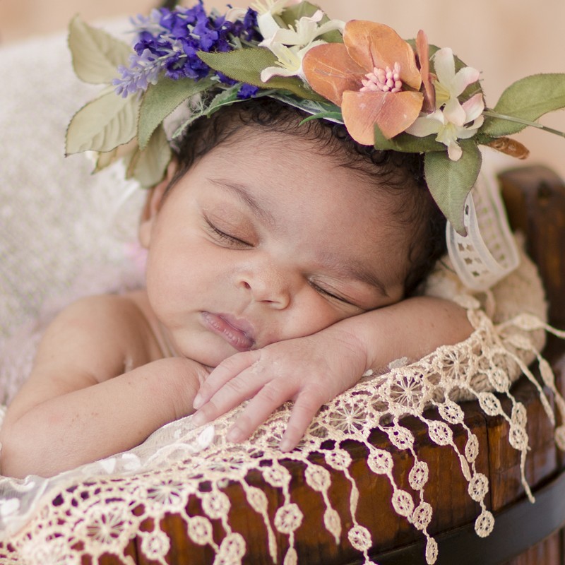 Newborn girl in brown bucket wiht lace and flowers