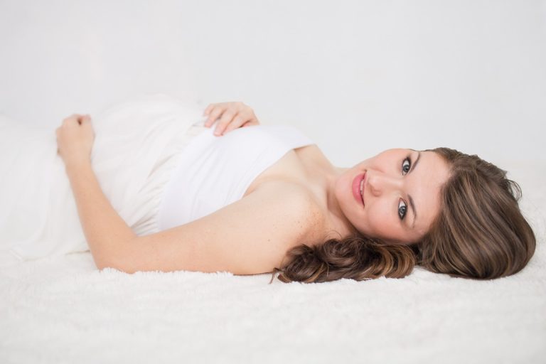 Pregnant mama in white lying on floor eyes to camers Gainesville Florida Maternity Photos