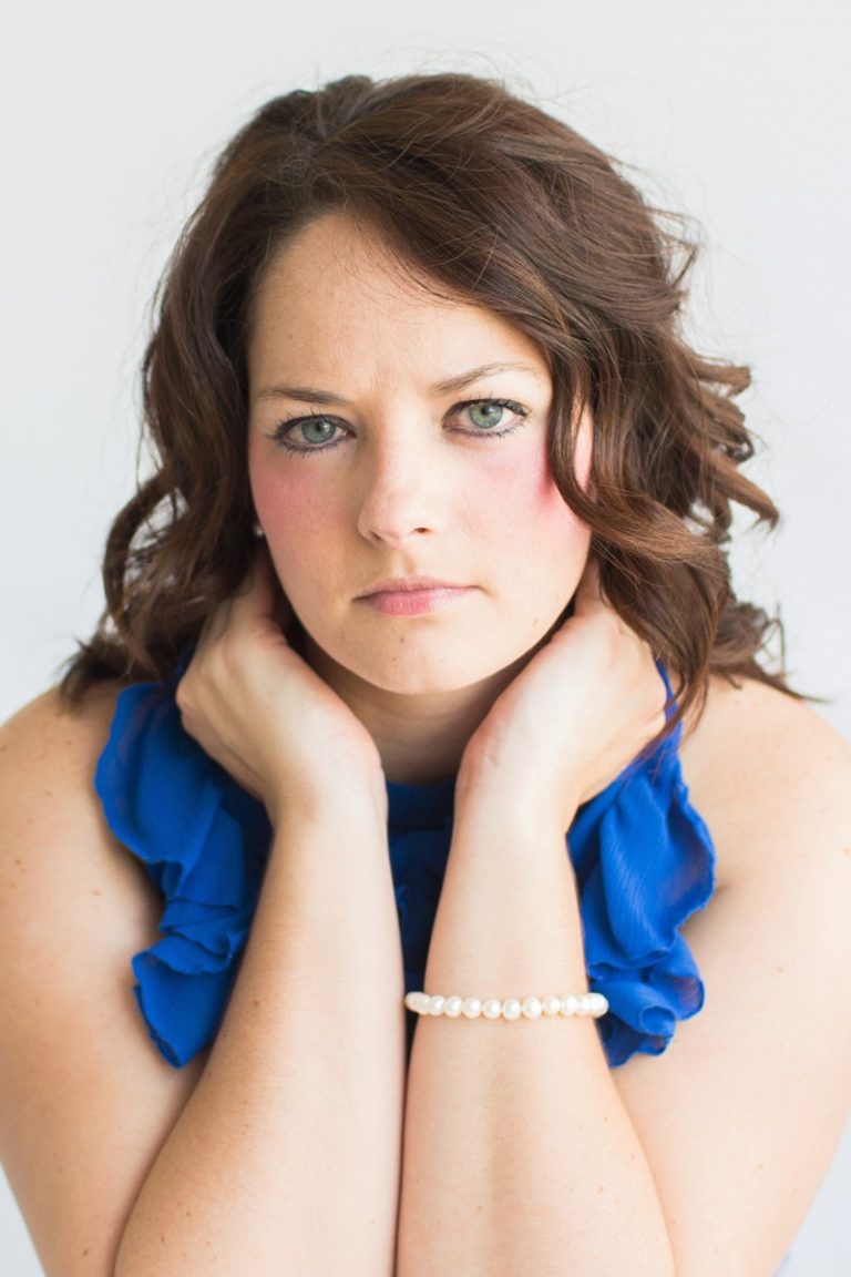 Beautiful woman big blue eyes brown curly hair hands cupped around chin celebrates beauty with glamor photos royal blue sleeveless ruffle dress Gainesville Florida Womens Portraiture