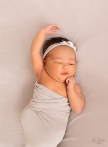 Newborn girl with ballet hands pose wrapped in grey