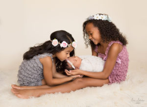 Joyful sisters loving newborn sister in Gainesville Florida