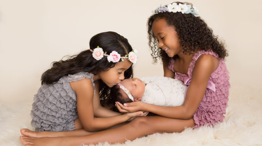 Joyful sisters loving newborn sister in Gainesville Florida
