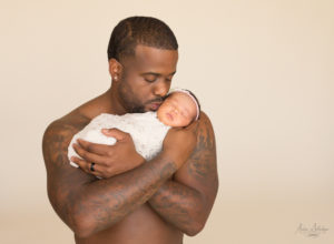 Dad with muscles and tatoos kissing his newborn girl
