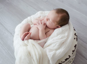 Newborn boy nude in shabby white crate with white blanket