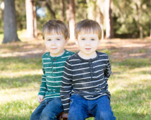 Shy two year old twin boys posed on bench