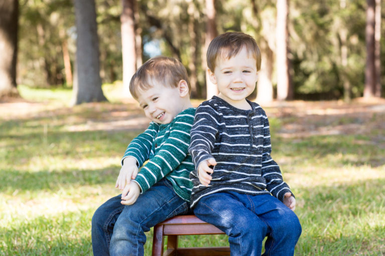 Family photo session at park with two year old twin boys laughing on bench