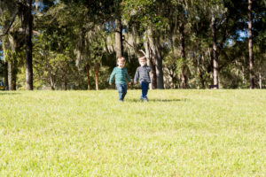 Family photo session at park with two year old twin boys walking