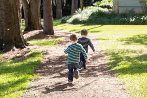 Two year old twin boys running at park