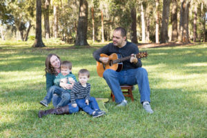 Family photo session at park with two year old twin boys Dad plays guitar