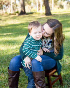 Family photo session at park with two year old twin boy getting kiss from mom