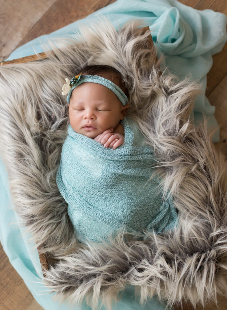 Babygirl in box in Newborn Photosession on Gray fur andAqua Baby Blanket