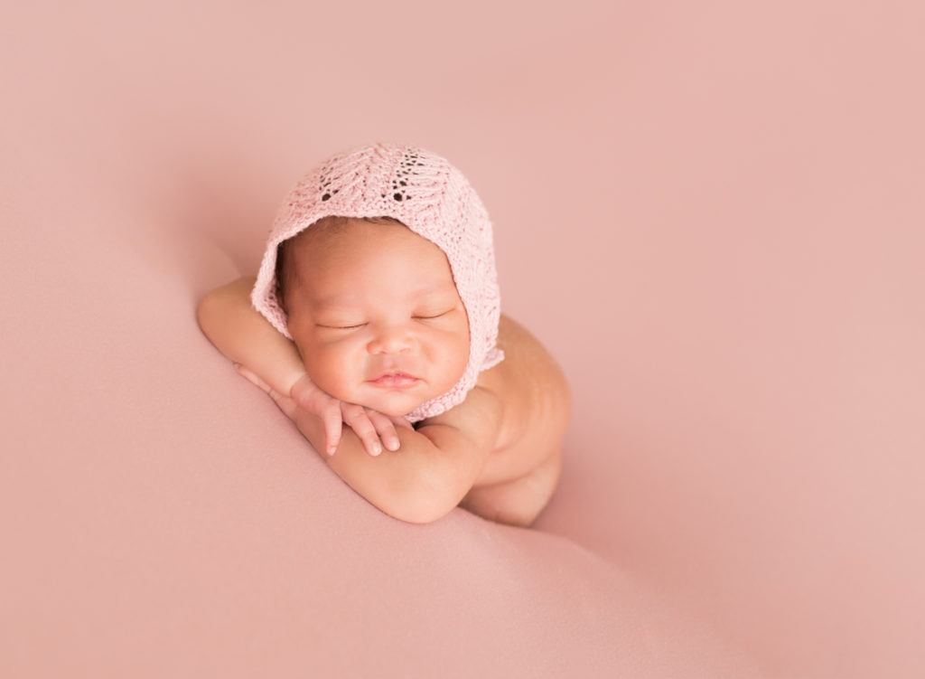Babygirl posed on arms in Newborn Photosession on Soft Pink Baby Blanket