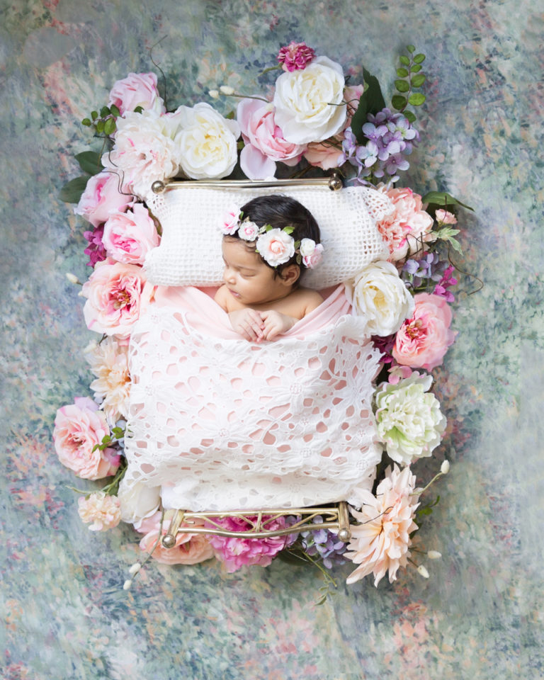 Newborn Girl Haven with full head of hair Pink and Peach Baby Bed on pastel flower background in Gainesville Florida