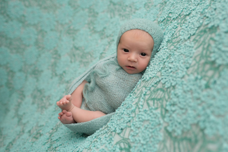 Baby girl Charleigh with eyes wide open all wrapped up in aqua on lace blanket and bonnet in Gaineville Florida