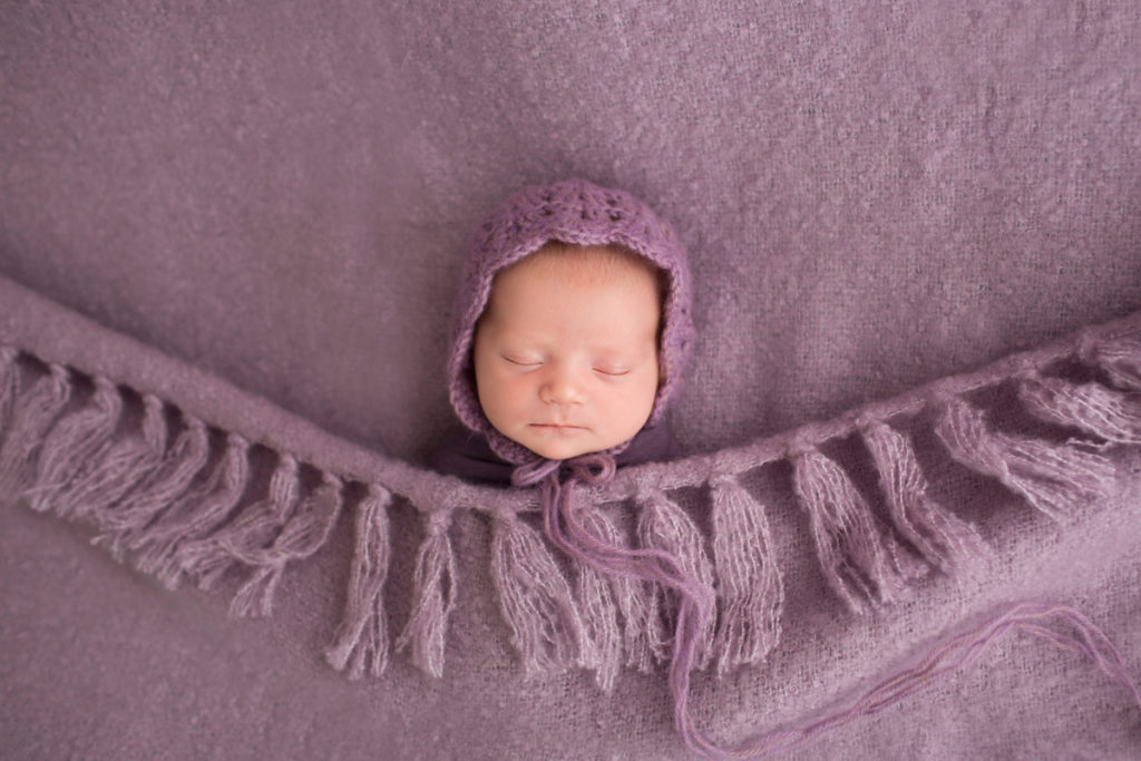 Baby girl Charleigh asleep tucked in purple bedspread and bonnet in Gainesville Florida