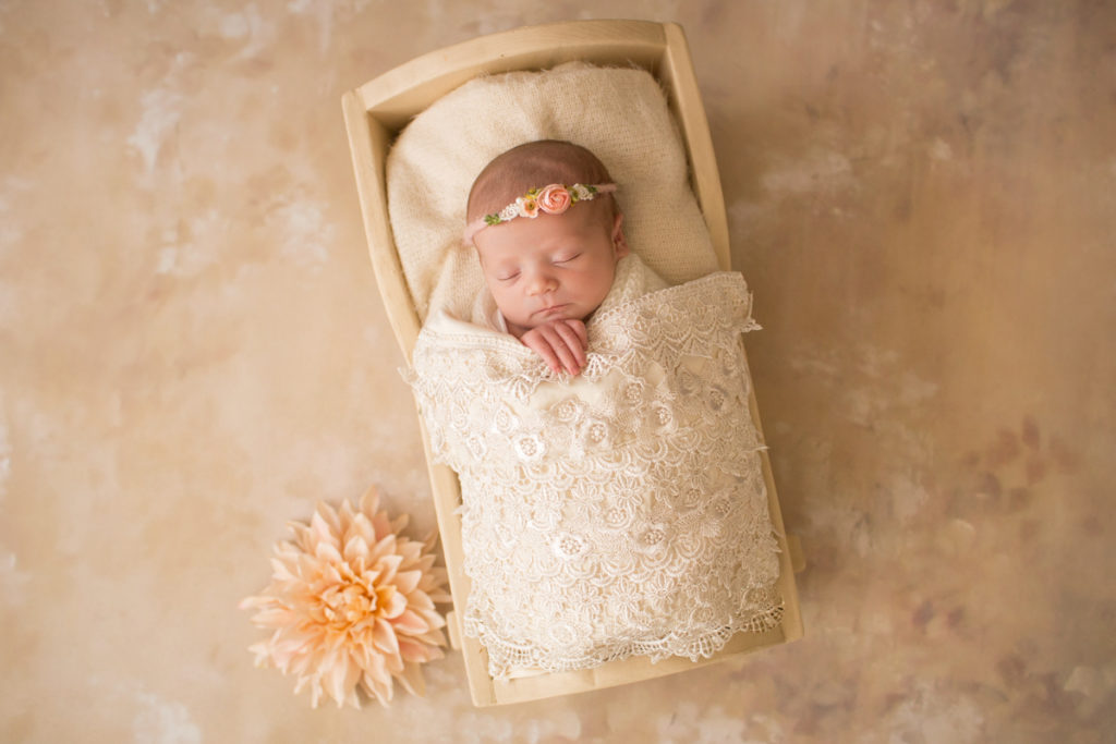 Baby girl Charleigh in cradle with lace and flowers and floral headband in Gainesville Florida