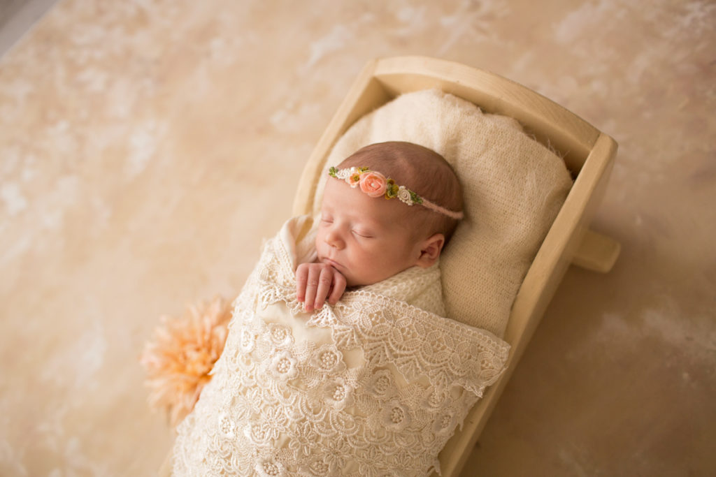 Baby girl Charleigh in cradle with lace and flowers in Gainesville Florida