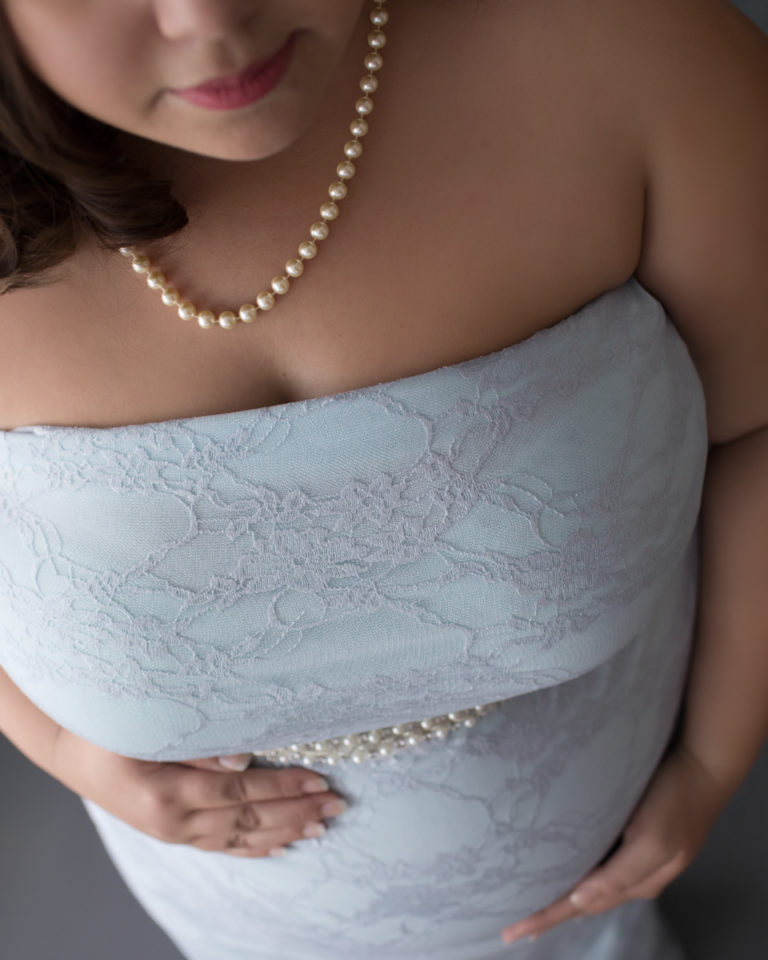 Elegant maternity Photos of Pregnant mom in Blue Lace gown and Pearls gazing down at baby belly in Alachua Florida