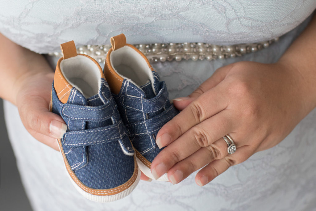 Maternity photos of Pregnant Adelis in Blue Lace gown and Pearls with baby booties in moms hand in Alachua Florida