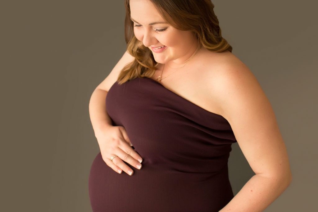 Maternity portrait gorgeous Janet looking down at baby James in burgundy gown Gainesville Florida