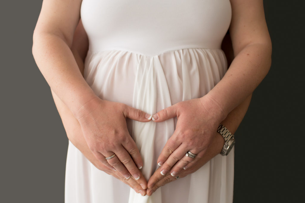 Maternity photo Janet and Nick heart hands on belly against white gownin Gainesville Florida