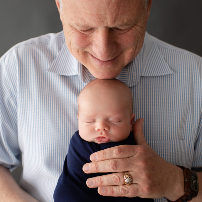 Proud Grandpa with big hands holding tiny newborn Gainesville Florida