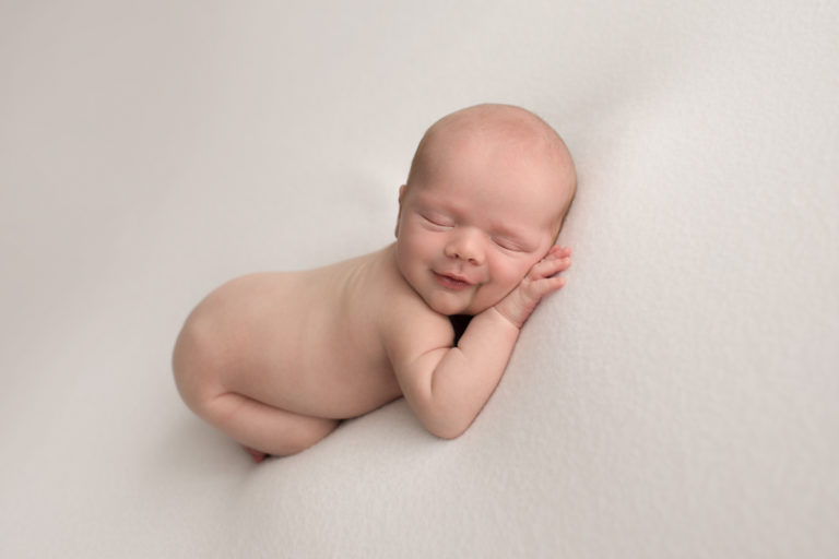 Naked newborn boy smiling on white blanket Gainesville Florida