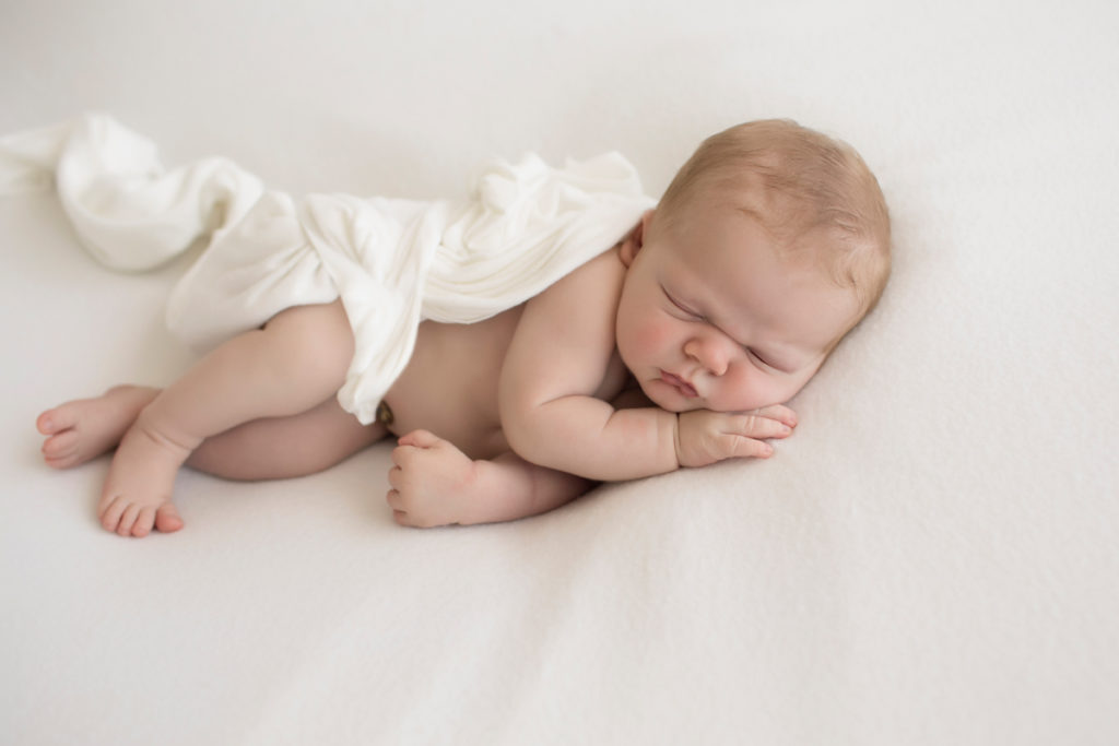Baby newborn boy asleep in white wrap on white blanket in Gainesville Florida