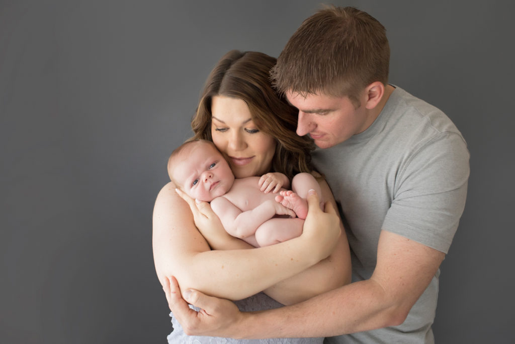 Mom and Dad cuddling naked baby newborn boy first family portrait in Gainesville Florida