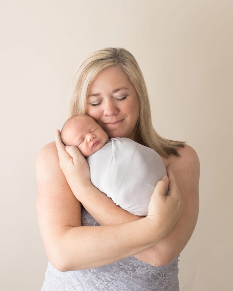 Photo mom in grey lace tenderly loving her newborn baby in grey knit