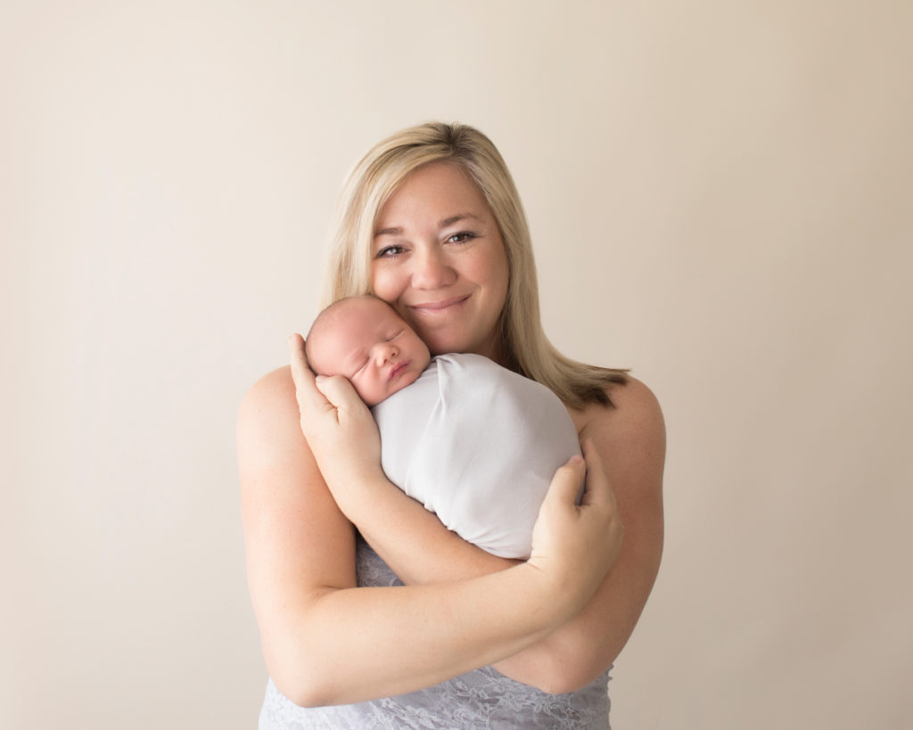 Photo mom in grey lace tenderly loving with tears of joy her newborn baby in grey knit