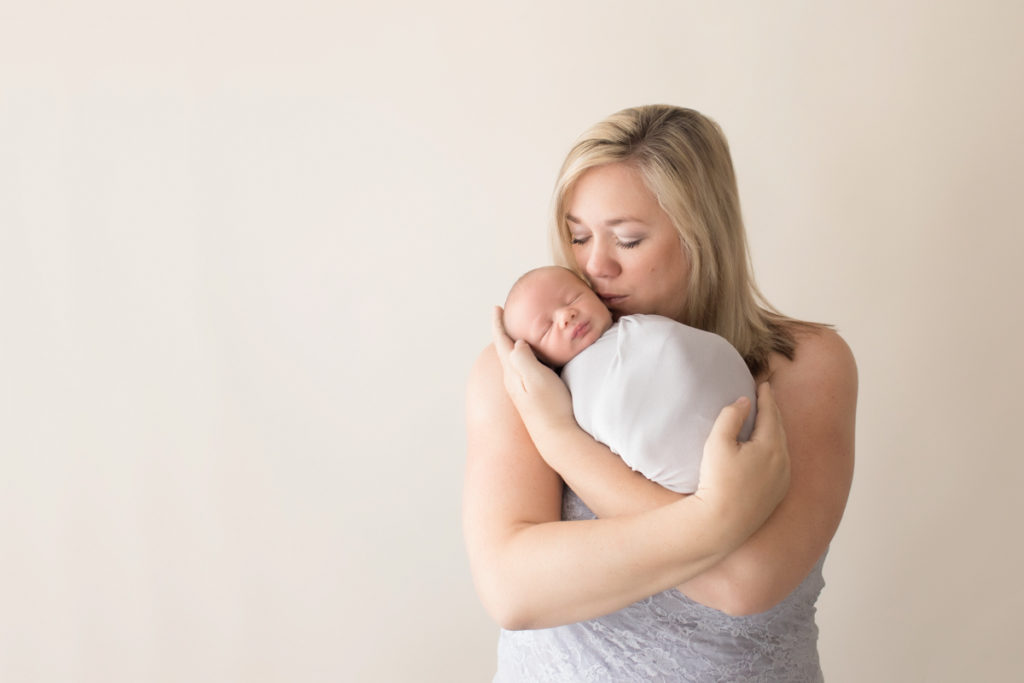 Photo mom in grey lace tenderly loving and kissing her newborn baby in grey knit