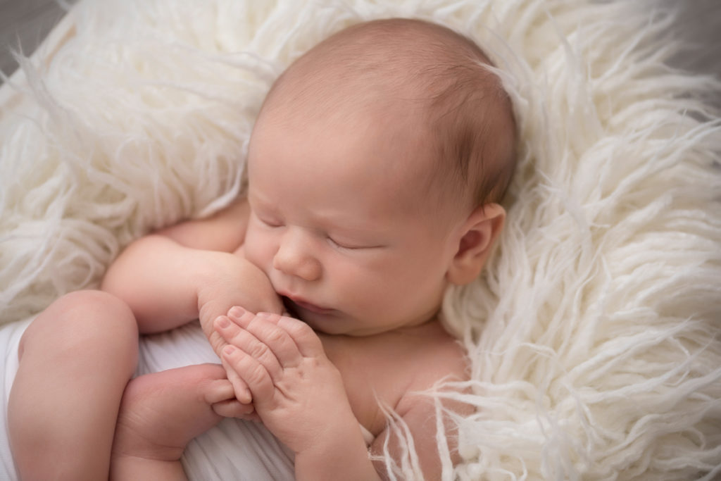 Naked baby newborn boy Chase in basket with white fluffy stuffer in Gainesville Florida