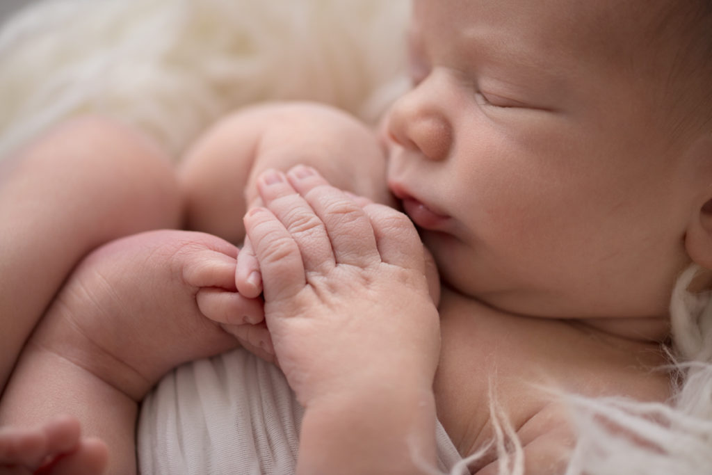 Naked baby newborn boy Chase close up of face hands feet with white texture in Gainesville Florida