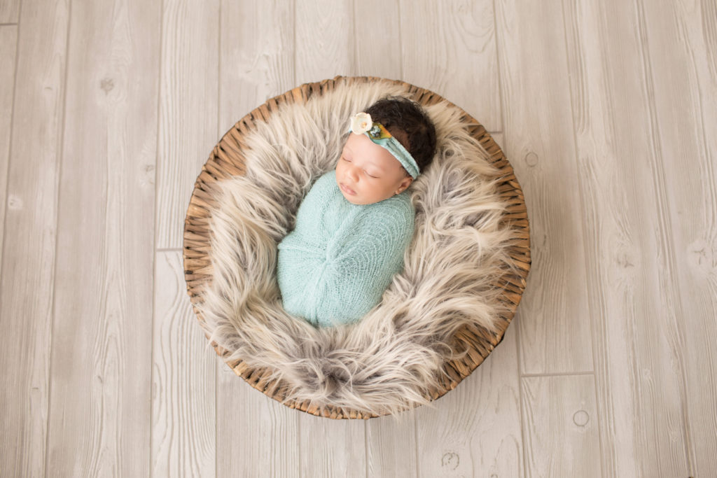 Newborn Girl Ayana wrapped in aqua shades onn grey fur and basket