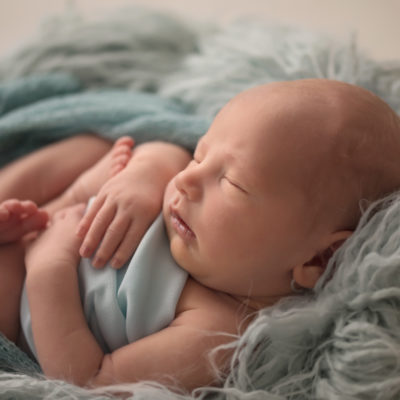 Soft and squishy Baby Jonah curled up in bowl with pale blue wrap and fluff with back light