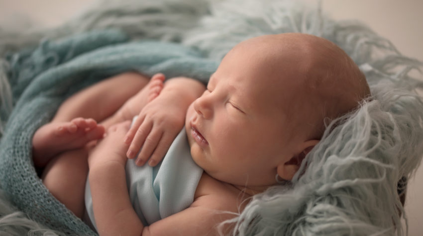 Soft and squishy Baby Jonah curled up in bowl with pale blue wrap and fluff with back light