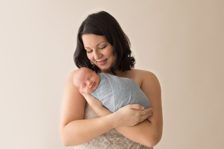 Smiling Mom Jen and smiling newborn son Jonah snuggling close dressed in shades of grey for baby and cream lace for mama