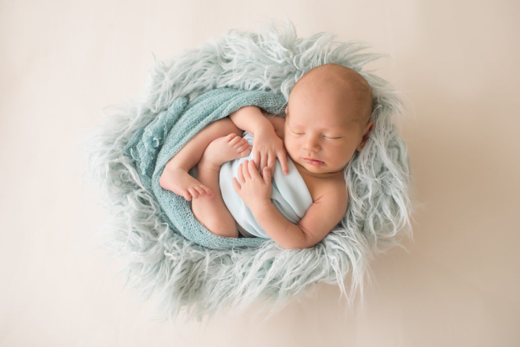 Soft and squishy Baby Jonah curled up in bowl with pale blue wrap and fluffy stuffer