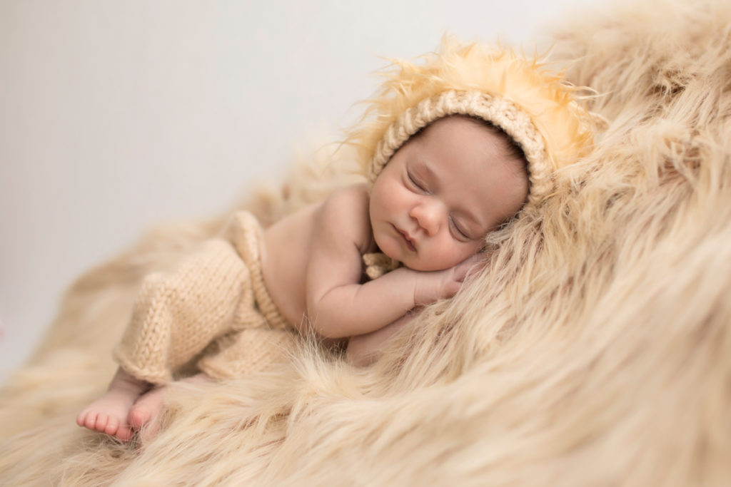 Baby boy Aidan in lion cub newborn outfit sleeping and posed on yellow fur